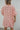 Back view of model wearing The Be A Star Sequin Dress which features pink sequins with gold sequin stars, a pink lining, half-length puff sleeves with elastic trim, side pockets, small side slits, and a back zipper and hook closure.