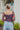 Back view of model wearing The Slow Down Top which features black mesh fabric with a multi-colored floral print, a lined bodice, a corset front with hook and eye closures, and long sleeves with elastic shoulders.