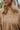 Close-up neckline view of model wearing the Don't Look Back Hoodie, which features light brown knit fabric, a henley neckline with tortoise buttons, a hood with drawstrings, a rounded hemline, and long sleeves with ribbed wrists
