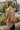 Side view of model wearing the Don't Look Back Hoodie, which features light brown knit fabric, a henley neckline with tortoise buttons, a hood with drawstrings, a rounded hemline, and long sleeves with ribbed wrists