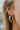Close view of model wearing the What A Twist Hoop Earrings, which feature open gold twisted hoops.