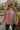 Close view of model wearing The Keep Me Warm Quilted Jacket which features quilted terracotta-colored fabric, two large front pockets, and a snap-up front with a collared neckline.
