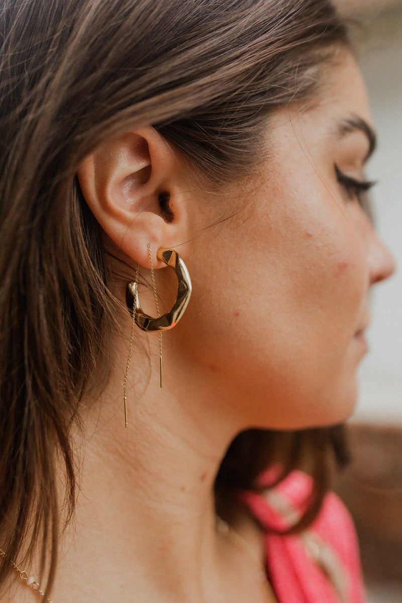 Side view of model wearing the Yours Truly Hoop Earrings, which feature open hold hoops with hammered detailing.