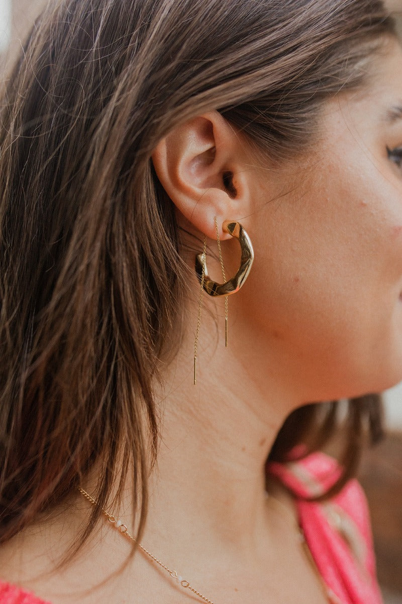 Side view of model wearing the Yours Truly Hoop Earrings, which feature open hold hoops with hammered detailing.