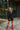 Full body view of model wearing The Call Me Rhinestone Fringe Dress which features black sweatshirt material, rhinestone fringe across the back and sleeves, a round neckline, and long sleeves with ribbed cuffs.