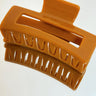 Aerial view of the Harper Hair Clip in Cognac, which is a light brown rectangular clip with claw teeth.