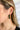 Side view of model wearing the Meet Me At Midnight Earrings which features green color emerald shaped hoops. 