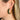 Side view of model wearing the Meet Me At Midnight Earrings which features green color emerald shaped hoops. 