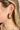 Side view of model wearing the Meet Me At Midnight Earrings which features green color emerald shaped hoops. 