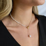 Close up view of model wearing the Mother Of Pearl Necklace features gold chain link with white beads linked with a gold circle lariat and pearl.