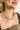 Close up view of model wearing the All That Glitters Necklace which features gold glitter and a thick chain link. 