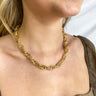 Close up view of model wearing the All That Glitters Necklace which features gold glitter and a thick chain link. 
