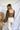 Back view of model wearing the Whirlwind Romance Top that has olive ribbed fabric, a corset style bodice with a square neckline, a cropped waist, and long sheer balloon sleeves with elastic wrists.