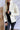 Close front view of model wearing the Yosemite Puffer Jacket that has ivory puffer fabric, two front pockets, black zipper details, a zip-up front, and a hood. Worn over black top.