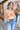 Front view of model wearing the Happy With You Tank Top that has beige knit fabric, a dark orange and light orange flower pattern, a cropped waist and spaghetti straps.