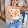 Front view of model wearing the Happy With You Tank Top that has beige knit fabric, a dark orange and light orange flower pattern, a cropped waist and spaghetti straps.