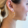 Side view of model wearing the Starburst Earrings which features gold open hoops with orange and peach beads.