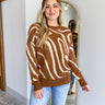 Front view of model wearing the Good Vibes Sweater that has brown and beige knit fabric with a cream swirl pattern, a round neckline, brown ribbed trim, and long sleeves
