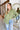 Front view of model wearing the Check It Out Top that has olive satin fabric with a monochromatic checkered pattern, two front chest pockets, a button up front with a collar, and long sleeves.