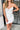 Close front view of model wearing the Ice Queen Dress that has white fabric with a metallic silver floral pattern, a strapless neckline with pleated ruffle detailing, a lining, and a back zipper closure