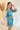 Side view of model wearing the Downtown Plans Dress which features light teal, sheen, satin fabric; square neckline, smocked back details and 3/4 sleeves with elastic and ruffle wrists.