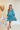 Full body view of model wearing the Downtown Plans Dress which features light teal, sheen, satin fabric; square neckline, smocked back details and 3/4 sleeves with elastic and ruffle wrists.