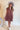 Full body front view of model wearing the Look At You Satin Dress that has terracotta satin fabric, two front chest pockets, v-neckline and cuffed short sleeves