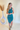 Full body view of model wearing the Over The Pines Dress which features dark green ribbed fabric, slit on the left side hem, round neckline and sleeveless.