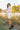 Full body side view of model wearing the Heading West Dress, that has ribbed cream fabric, fitted long sleeves, a mock neck, ruching on one side, and a cream lining