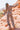 Full body back view of model wearing the Desert Daze Pants, that feature pleated fabric with a black and taupe print, an elastic waist, lettuce edge details, and black lining. worn with matching top.