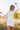 Front view of model wearing the Heading West Dress, that has ribbed cream fabric, fitted long sleeves, a mock neck, ruching on one side, and a cream lining