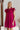 Frontal view of the Perfect Pair Dress that features a magenta material, a high rounded neckline with a ruffle detail, a short ruffle sleeve, a pleated top, a tiered design, a back button closure, a flowy fit, and a mini length.