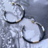 The Muted Moment Earring is a hoop style earring, featuring black, white, and grey beading through out.