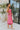 Side view of the Pink Dreams Dress that features a monochromatic pink houndstooth pattern, a cowl neckline, a sleeveless design with thin adjustable straps, and a side slit.