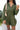 Front view of model wearing the One Way Ticket Romper, that features olive fabric, wood button closures, v neckline, two front pockets with tie details and balloon long sleeves with elastic wrists
