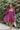Frontal view of the Wanderlust Dress that features a wine colored silk material, a straight neckline, a puffy half sleeve, a smocked back, and a mini length.