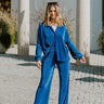 Full body view of model wearing the Be You Pants which features royal blue pleated fabric, elastic waistband and flare pant with lettuce detail on the hem.