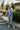 Full body view of model wearing the Have You Heard Shacket features purple corduroy fabric, two front pockets, silver button up closures, a collared neckline, waffle knit side detailing, a high- low hem, and long balloon sleeves with button closure wrists