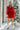 Close up view of model wearing the In The Spirit Dress which features red sheen fabric, a surplice neckline, a lining, an elastic waist with a tie, a ruffle hem, and balloon sleeves with elastic wrists.
