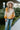 Close up view of model wearing the Autumn Skies Sweater which features light orange, bright orange and rust knit fabric, diagonal stripe pattern, round neckline with ribbed knit fabric and long ballon sleeves with ribbed knit fabric wrists.