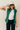 Front view of model wearing the Naya Hunter Green Athletic Vest which features green light weight puffer fabric, a thick hem, a monochromatic front zipper, two front pockets with zipper closures, a high neckline and a sleeveless design.