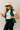 Side view of model wearing the Naya Hunter Green Athletic Vest which features green light weight puffer fabric, a thick hem, a monochromatic front zipper, two front pockets with zipper closures, a high neckline and a sleeveless design.