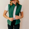 Front view of model wearing the Naya Hunter Green Athletic Vest which features green light weight puffer fabric, a thick hem, a monochromatic front zipper, two front pockets with zipper closures, a high neckline and a sleeveless design.