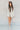 Full body front view of model wearing the Blaire Natural High-Waisted Shorts that have lightweight natural fabric, pockets, a front zipper with a tortoise button closure, and belt loops. Worn with matching blazer