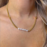 Close up view of model wearing the Keep A Secret Pearl Necklace which features two different gold chain designs linked with pearls and a gold lock.