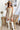 Full front view of model wearing the Desert Sands Skirt that has natural colored fabric, an open knit crochet design, natural colored lining, mini length, and a drawstring tie with tassel details at the waistband