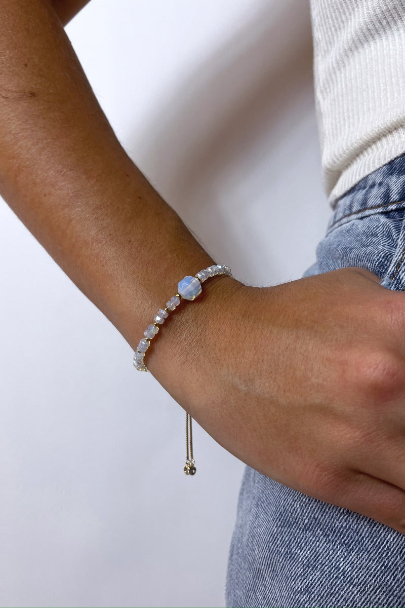 Front view of model wearing the Cold As Ice Bracelet which features iridescent and gold beads with an adjustable string.