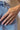 Close up view of model wearing the Remember Me Ring which features four-layered gold ring bands, one band has three square shaped clear stones, second band has gold beads, third band is covered with clear stones and fourth band has a single clear stone.