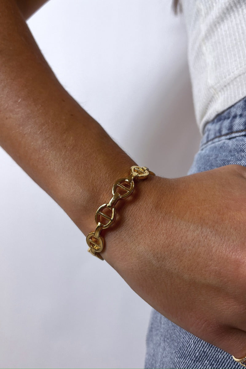 Close up view of model wearing the Break The Chain Bracelet which features gold adjustable bangle with gold chain link design.