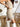Close side view of model wearing the Desert Sands Skirt that has natural colored fabric, an open knit crochet design, natural colored lining, mini length, and a drawstring tie with tassel details at the waistband
